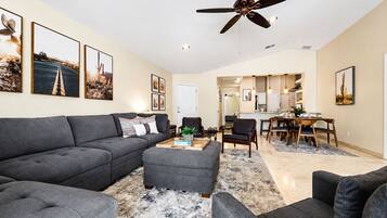 A modern living room with a grey sofa, a coffee table, and a ceiling fan.
