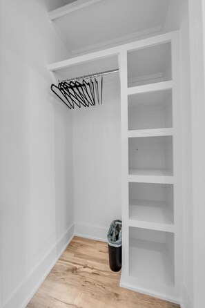 Ein begehbarer Kleiderschrank mit Kleiderstange und Mülleimer.