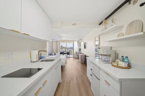 Una cocina moderna con una isla central, un comedor con vistas y un espacio de sala con sofá y televisor.
