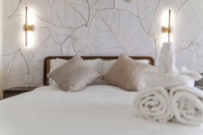 A hotel room with a bed, two pillows, a headboard, and a wall with leaf patterns. - 36FL New Cozy Apartment Great View Central Waikiki (Honolulu)