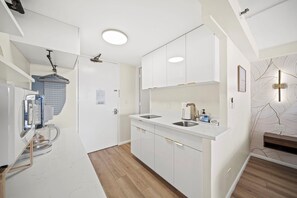 A modern kitchen with white cabinets, a sink, and a coffee machine. - 36FL New Cozy Apartment Great View Central Waikiki (Honolulu)