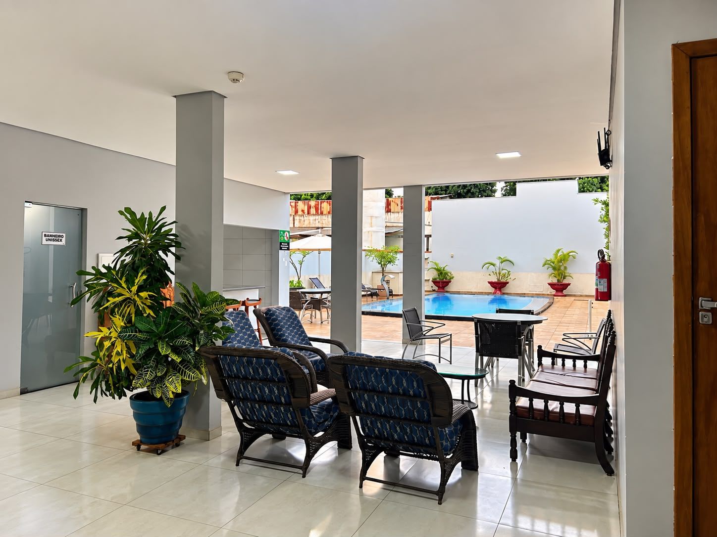 A hotel lobby with a pool area, seating arrangements, and potted plants.