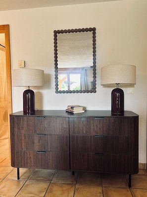 A dark wooden cabinet with two lamps, a mirror, and a small stack of books. - Spacious 3-bed, 3-bath flat in the centre of Verbier. Pet-friendly! (Val de Bagnes)