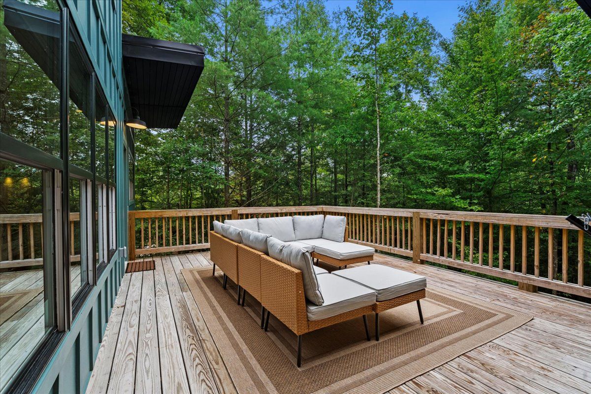 A wooden deck with a wicker sofa and a small table, surrounded by a wooden railing.