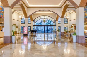 Eine geräumige Lobby mit hoher Decke, Bogenfenstern und einem zentralen Kronleuchter.