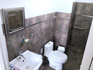 A bathroom with a white sink, toilet, and a shower area. - Lunawasi Hospedaje (LUNAHUANA)