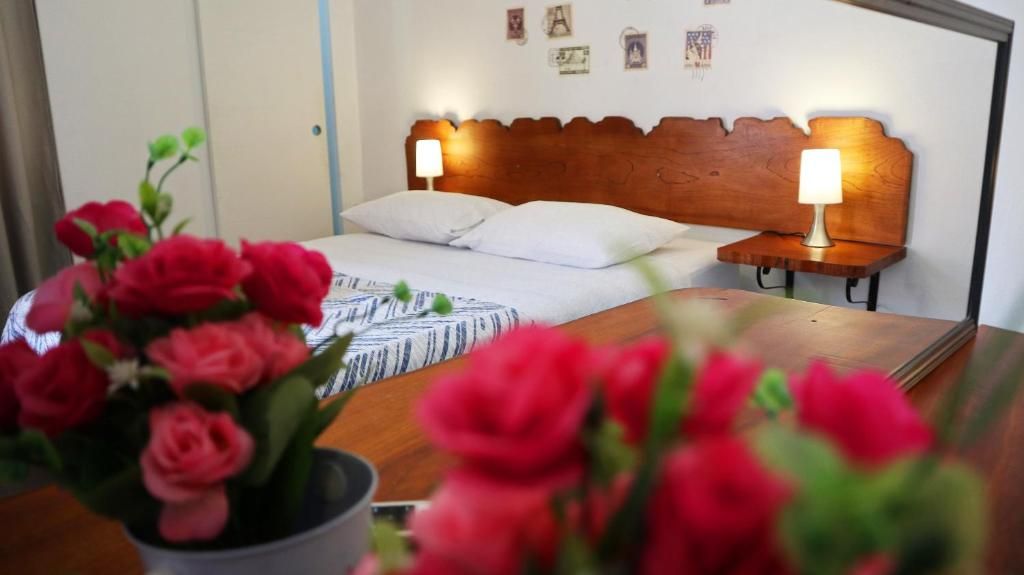 Habitación de hotel con cama, lámparas de noche y un arreglo floral.