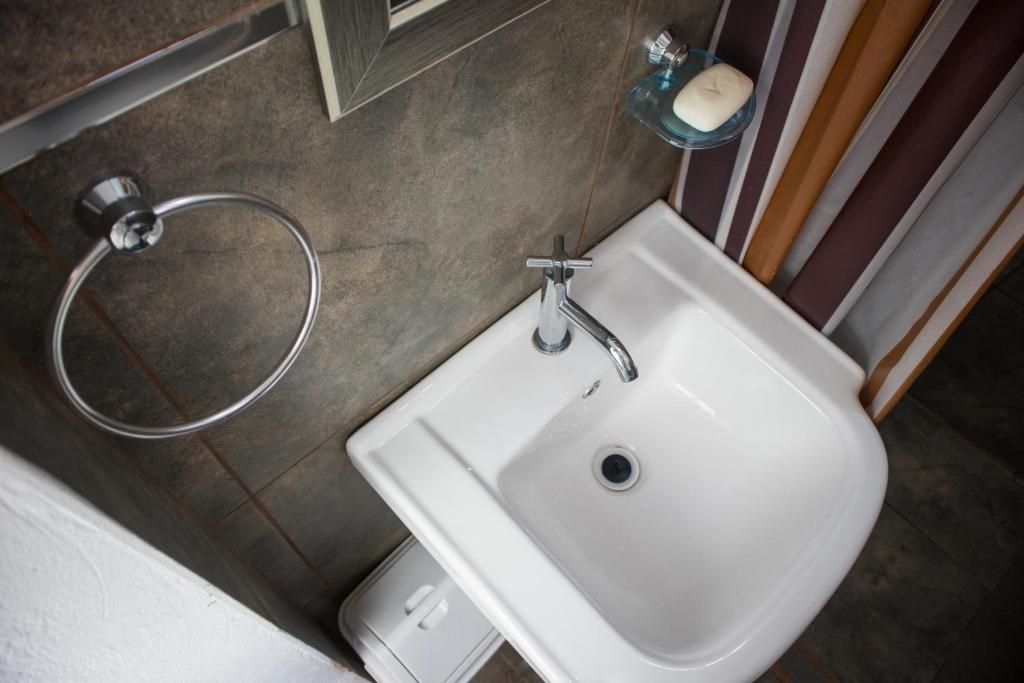 Un baño con un lavabo blanco, un tocadela toallas y un jabonera.
