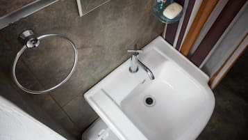 Un baño con un lavabo blanco, un tocadela toallas y un jabonera.