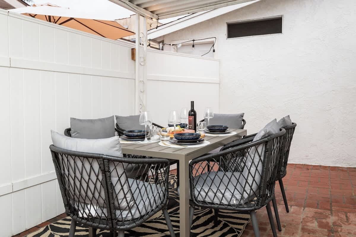 Een eethoek met een tafel gedekt voor vier personen, omringd door rieten stoelen met kussens.