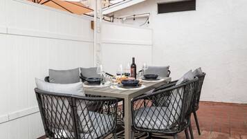 Een eethoek met een tafel gedekt voor vier personen, omringd door rieten stoelen met kussens.