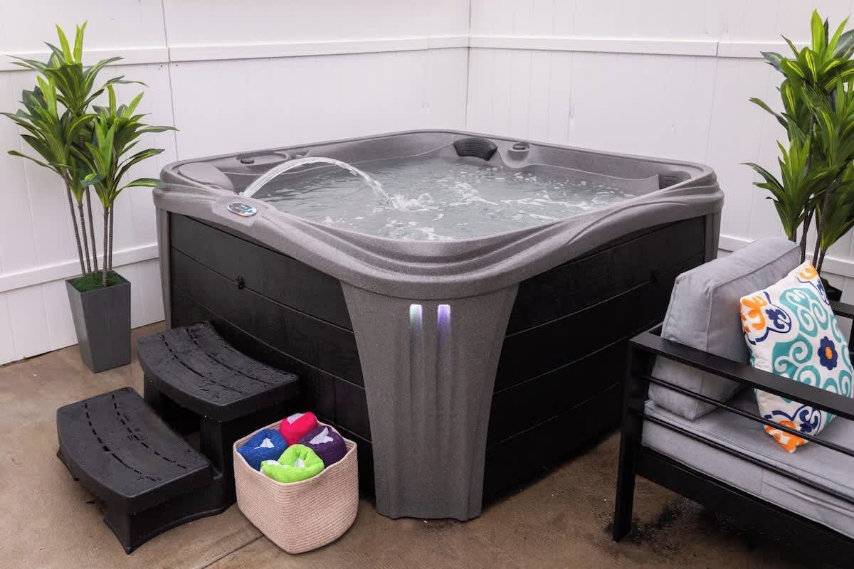 Ein Wellnessbereich mit Whirlpool, Treppen, einer gepolsterten Sitzbank und Topfpflanzen.