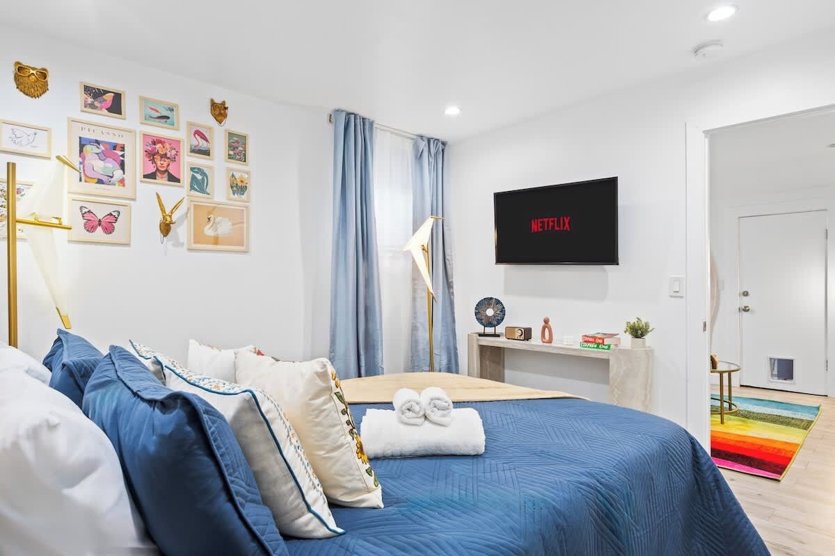 Ein modernes Schlafzimmer mit einem Bett, einem Schreibtisch, einem Fernseher und unterschiedlichen Wanddekorationen.