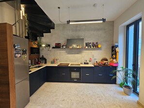 A modern kitchen with a central island, dark cabinetry, and a large window providing natural light. - Marseille, 5th arrondissement: 140 m² duplex + garden + air conditioning (Marseille)