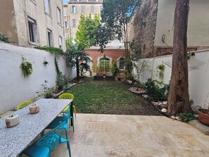 A courtyard with a table and chairs, surrounded by buildings and trees. - Marseille, 5th arrondissement: 140 m² duplex + garden + air conditioning (Marseille)