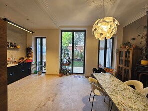 Cozinha moderna com área de jantar, janelas amplas e luminária decorativa.