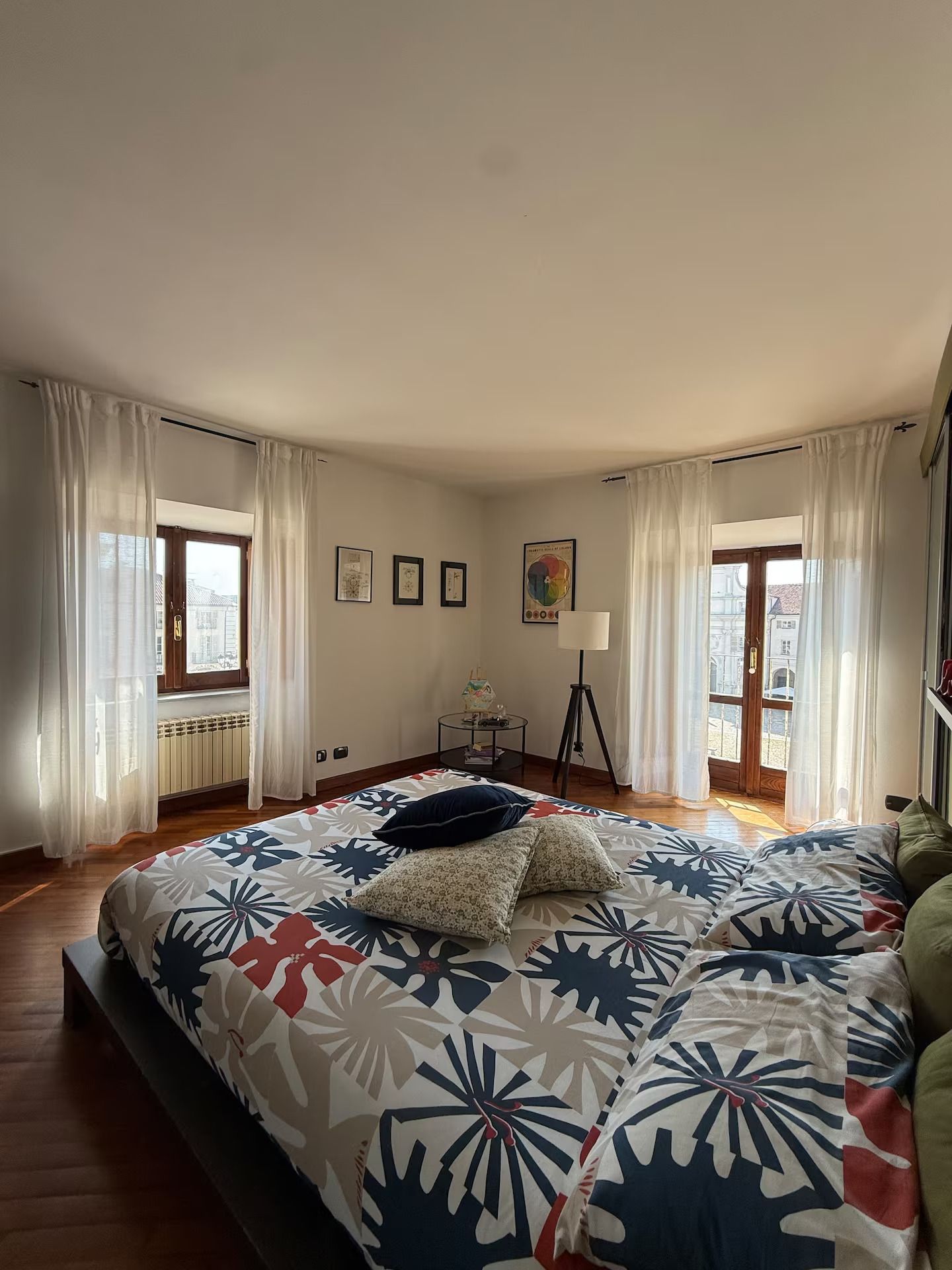 Una camera da letto con un letto grande, una lampada da terra e una finestra con tende.