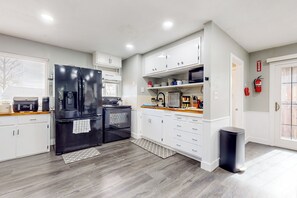 A modern kitchen with white cabinets, a black refrigerator, a microwave, and a coffee machine. - Peace at the River -Private Dock, Games, & FirePit (Bethel Island)