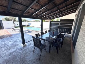 Eine Außenpatio mit überdachter Essgegend, einem Pool und Blick auf die umliegende Nachbarschaft.