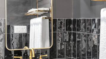 A bathroom with a gold-framed mirror, a sink with gold faucets, and black marble tiles.
