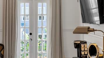 Une chambre d’hôtel avec un lit, un bureau doté d’une machine à café, une télévision et une grande fenêtre avec des rideaux.