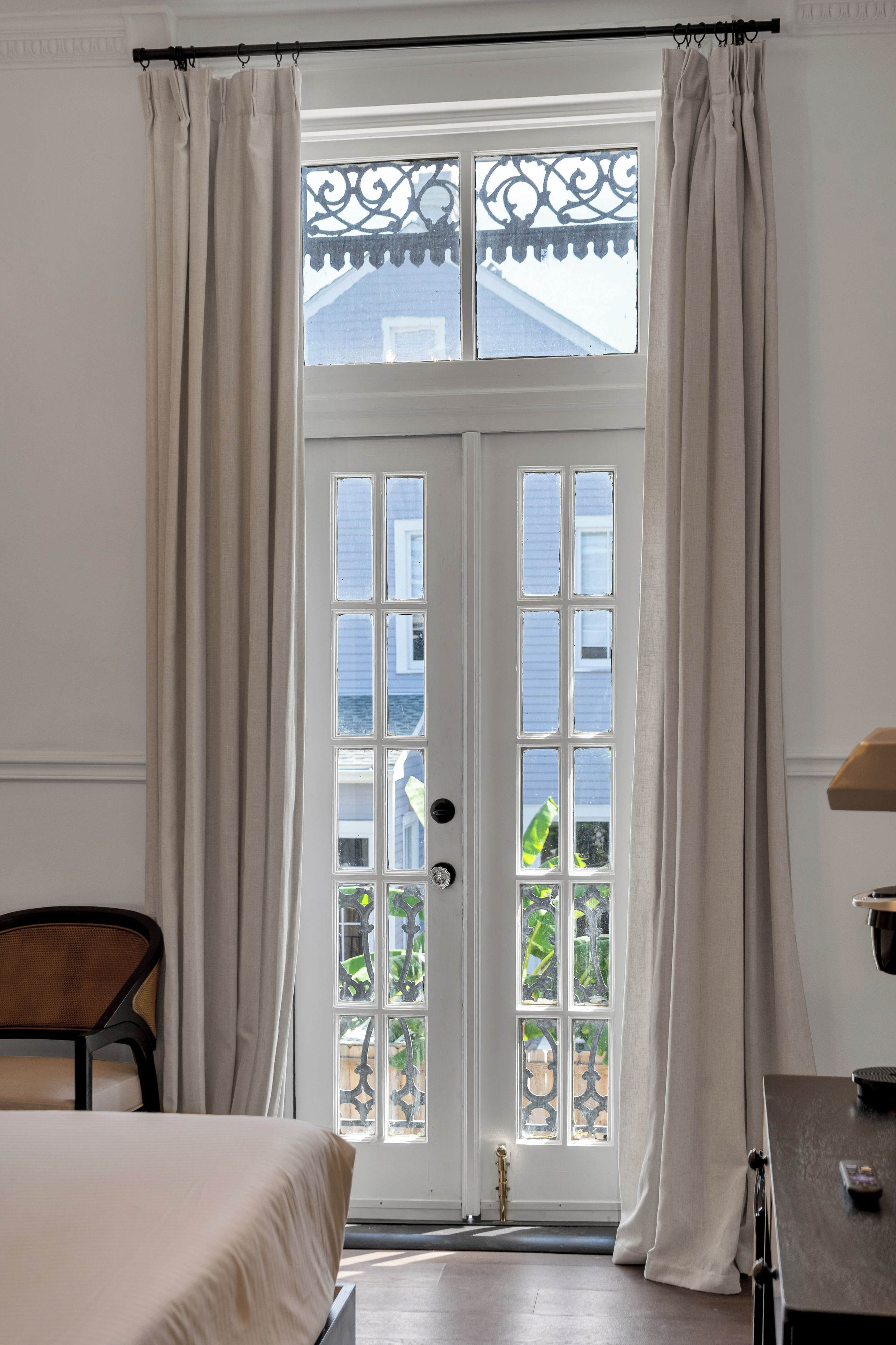 A room with a large window, a bed, a chair, and a table.