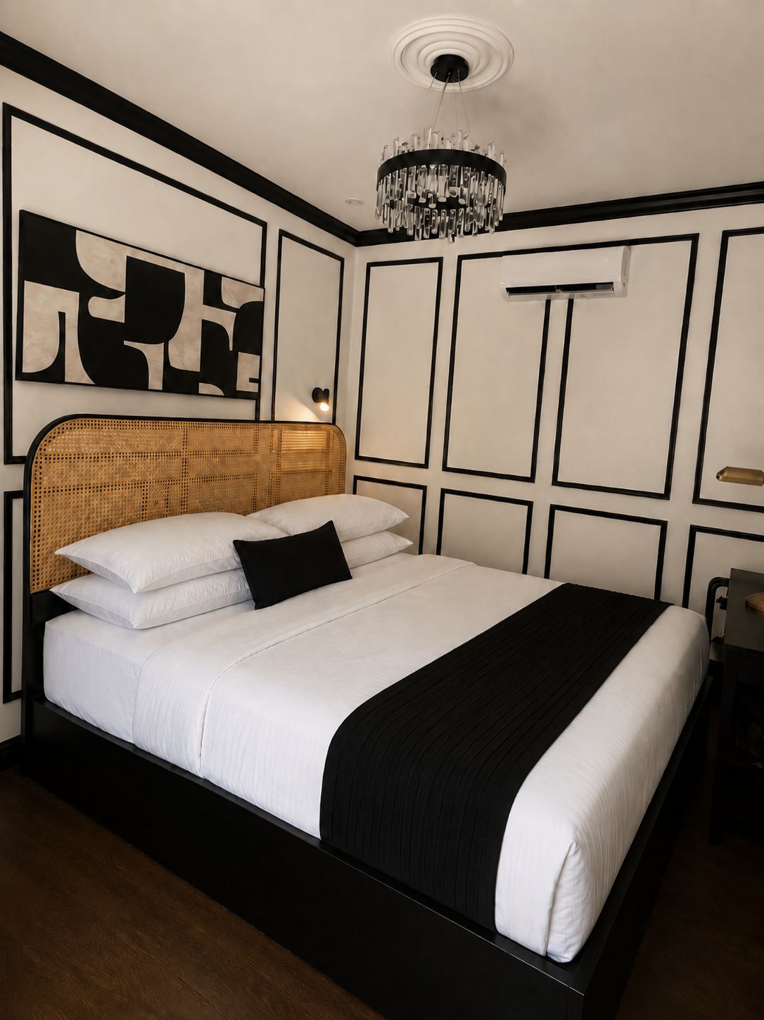 Un lit bien fait, avec une tête de lit noire, une literie blanche et un plaid noir.