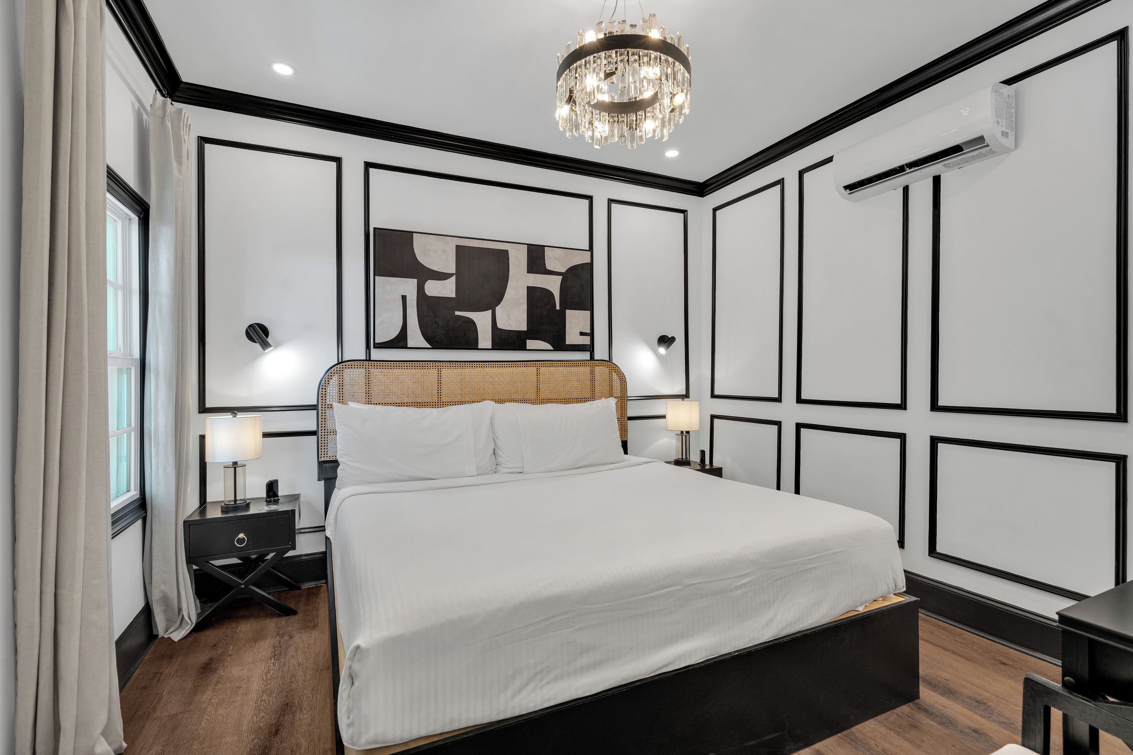 Een moderne slaapkamer met een groot bed, nachtlampjes, een kroonluchter en een wandairconditioner.