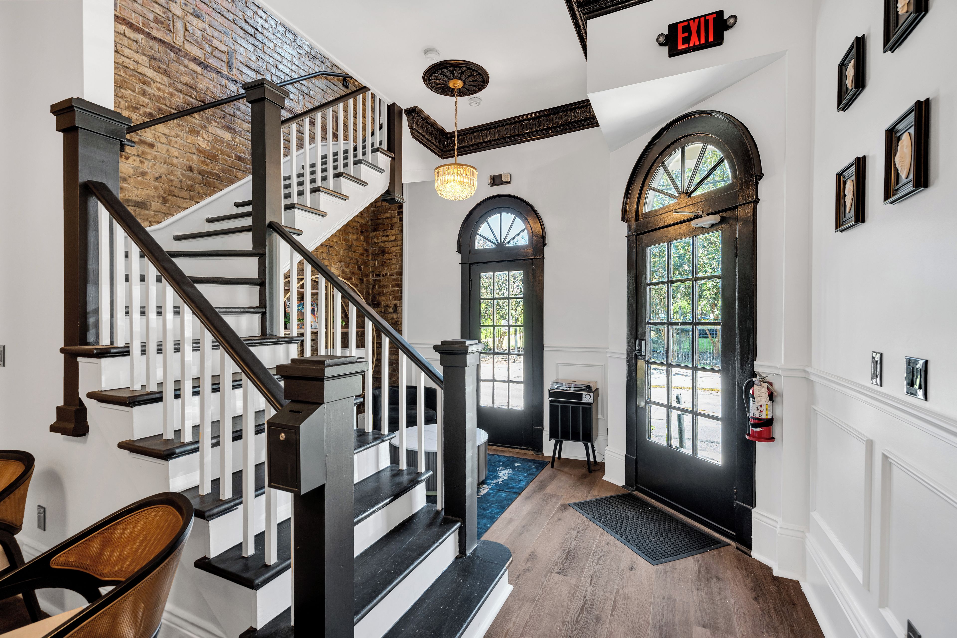 A staircase with a black railing, a chandelier, and a door with a window.