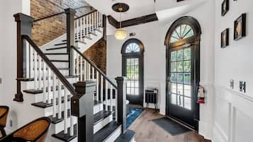 A staircase with a black railing, a chandelier, and a door with a window.