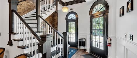 A staircase with a black railing, a chandelier, and a door with a window.