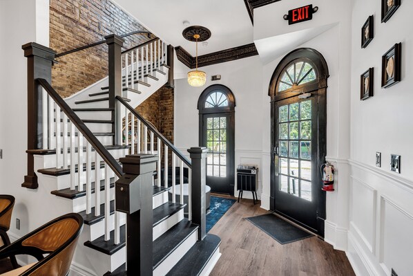 A staircase with a black railing, a chandelier, and a door with a window.