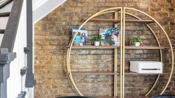 Un intérieur moderne avec un mur en briques, un escalier et une étagère circulaire en métal remplie de livres.