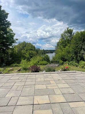 A paved patio area with a view of a lake and surrounding greenery. - Spacious 4-bedroom house in beautiful Elliot Lake. Close to all trails and town. (Elliot Lake)