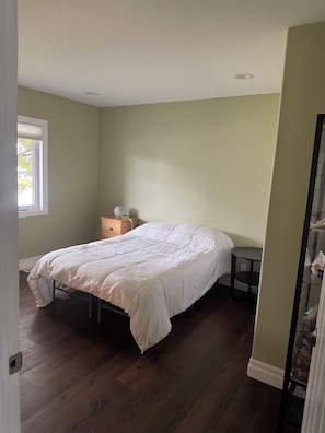 A bedroom with a bed, a bedside table, a dresser, and a window. - Spacious 4-bedroom house in beautiful Elliot Lake. Close to all trails and town. (Elliot Lake)