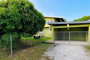 Een woonhuis met een omheinde tuin, een overdekte garage en een duidelijke trap naar een tweede verdieping.