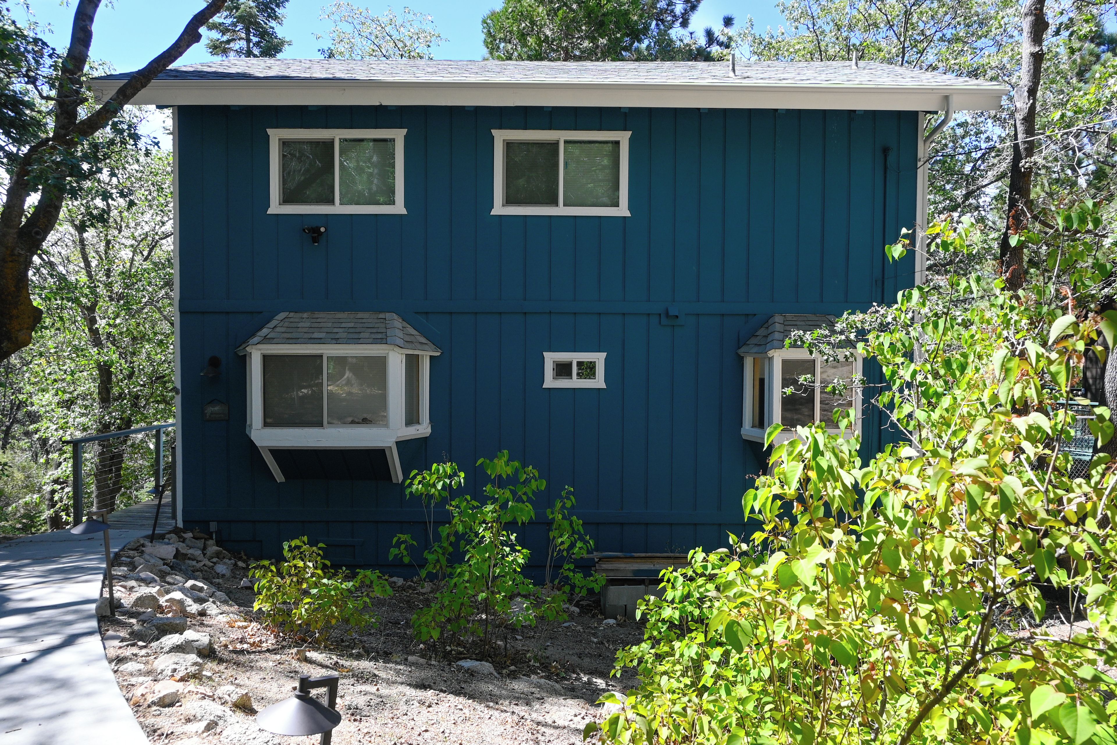 A two-story building with a blue exterior, two windows on the upper floor, and a small porch area with a single window.