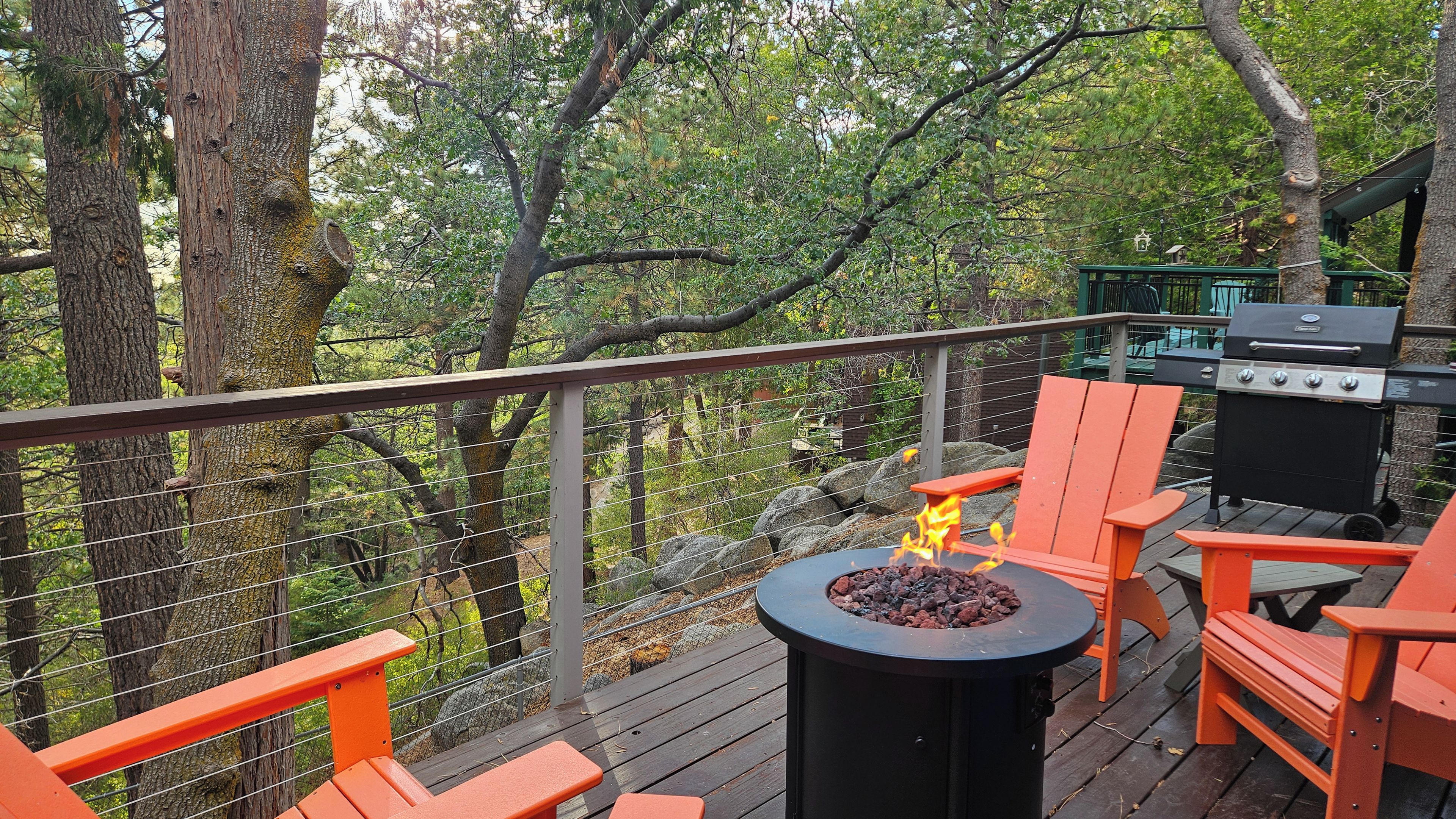 A deck with a fire pit, outdoor seating, and a grill.