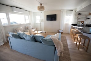 Una sala de estar moderna con un sofá, una mesa de centro y un televisor montado en la pared.