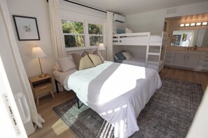 Un dormitorio con cama, mesita de noche, lámpara, litera, espejo y ventana.