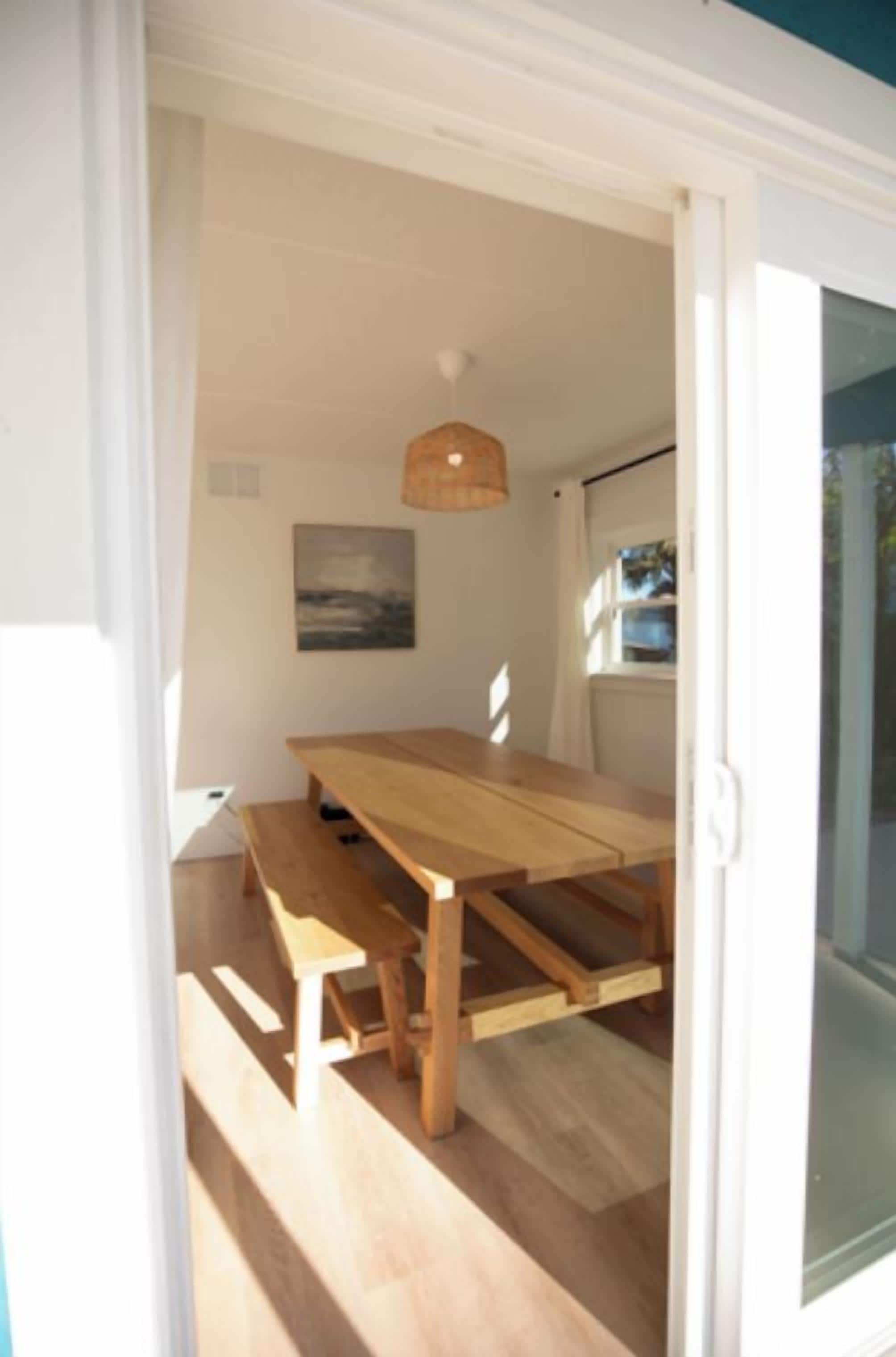A wooden dining table with benches in a room with a white ceiling and a hanging light fixture.