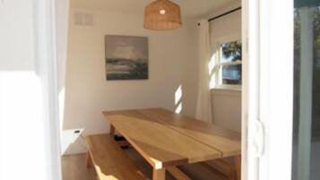 A wooden dining table with benches in a room with a white ceiling and a hanging light fixture.