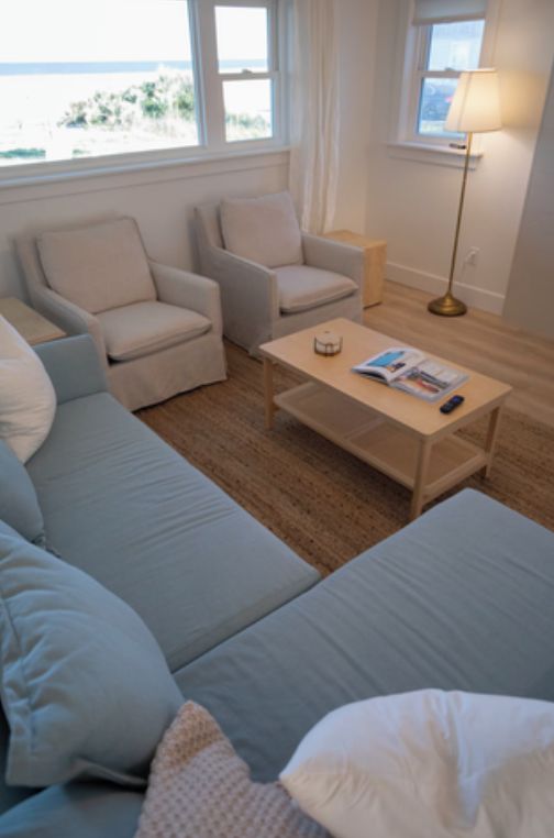 Quarto com sofá, poltronas, mesa de centro com uma revista e abajur.