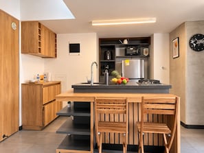 A modern kitchen with a central island, wooden cabinets, a stainless steel refrigerator, and a clock on the wall. - Amazing Loft in Medellín—Central (Medellín)