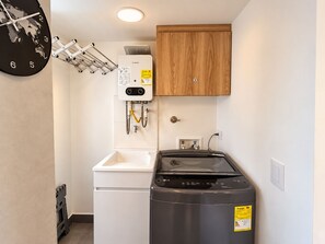 Cozinha compacta com aquecedor Bosch, pia e máquina de lavar LG.