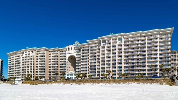 A large hotel with multiple floors and balconies, located near a beach.