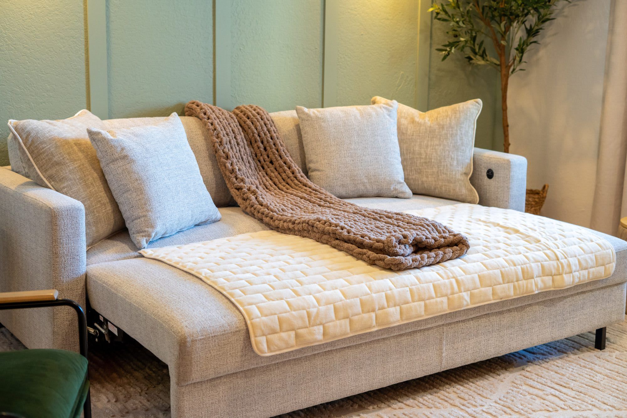 A sofa with a knitted throw blanket and a quilted throw.