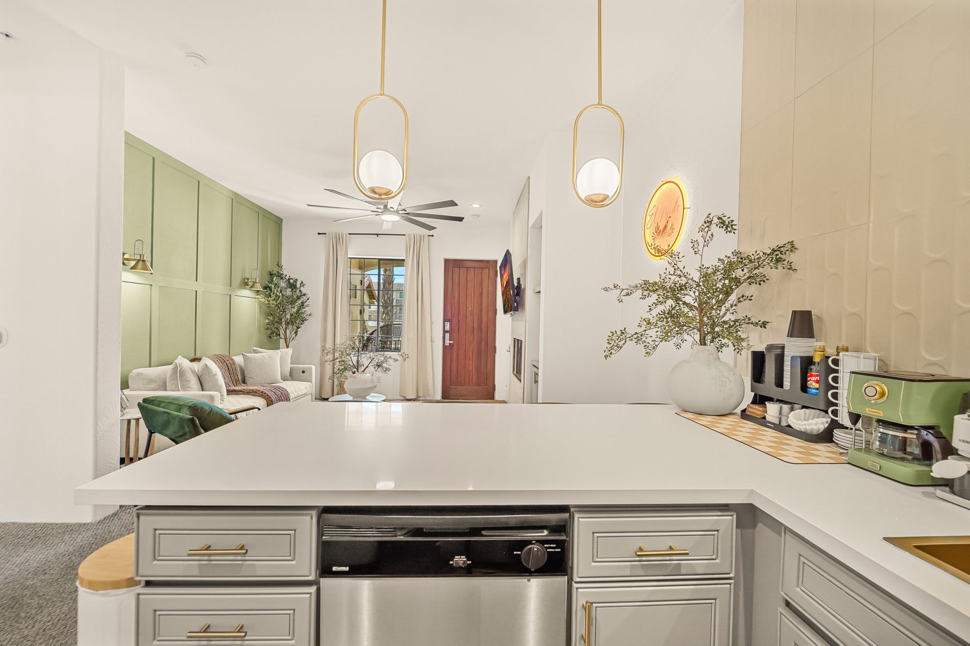 A modern kitchen with a central island, built-in appliances, and a dining area with a green accent wall.