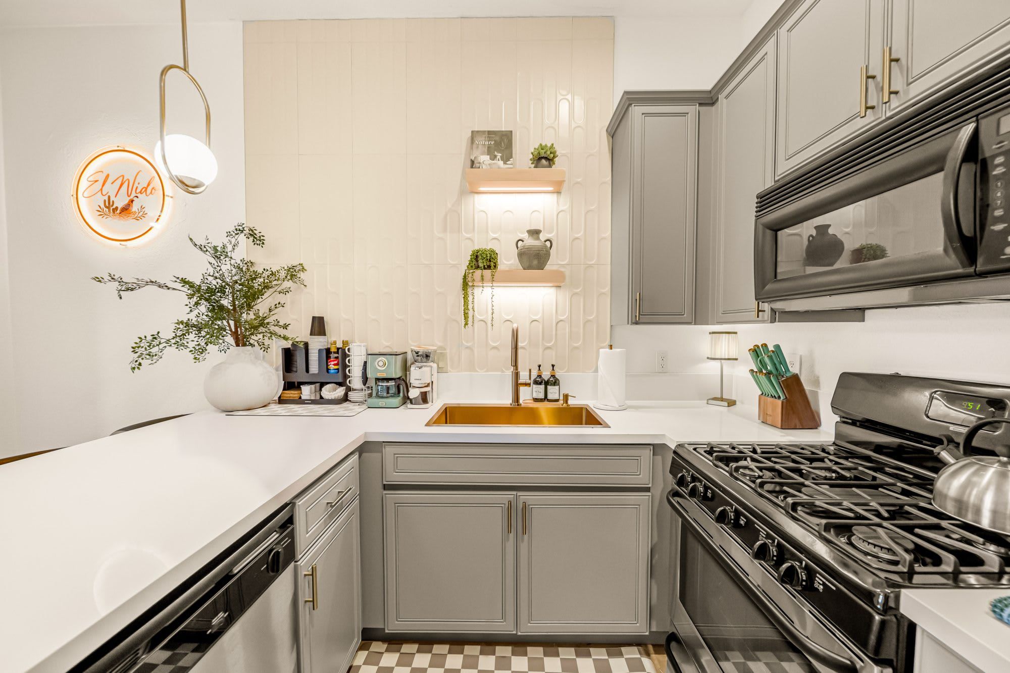 Une cuisine moderne dotée d’un îlot central, d’appareils électroménagers en acier inoxydable et d’un carrelage à motifs géométriques.