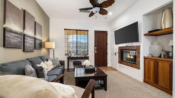 A living room with a sofa, coffee table, fireplace, television, and artwork on the wall.